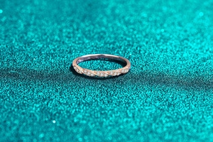 Detailansicht eines roségoldenen verdrehten Rings mit Kristallen auf grünem Hintergrund
