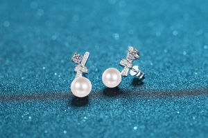 Detailed macro view of S925 sterling silver bow earrings with shiny pearls and zircon crystals