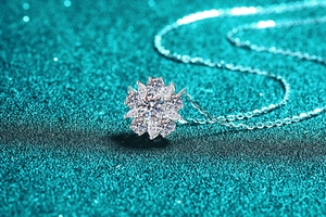 Macro shot of silver sunflower moissanite pendant on a blue shimmering background