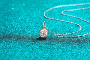 Macro d'un pendentif coeur en moissanite or rose sur fond bleu scintillant élégant