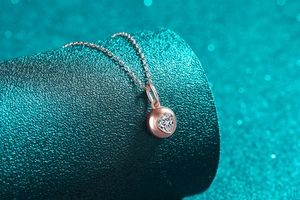 Détail macro du pendentif cœur en or rose avec moissanite brillante sur fond bleu