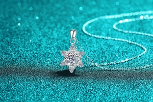 Macro detail of S925 sterling silver snowflake pendant with moissanite stones on teal glitter