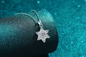 Macro view of S925 sterling silver snowflake pendant with moissanite on green stand