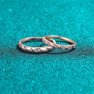 Elegant pair of rose gold couple rings with micro-set diamonds on a teal sand background