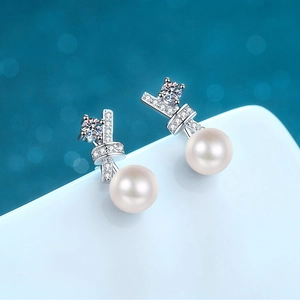 Elegant S925 silver pearl bow earrings with sparkling cubic zirconia on a white display