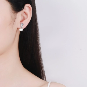 Elegant S925 silver bow stud earrings with white pearl pendants on a female model