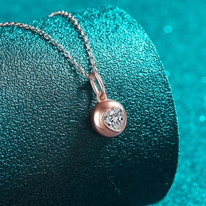 Élégant collier pendentif moissanite en forme de cœur or champagne sur un support vert texturé