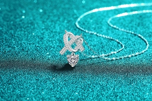 Détail du collier cœur en moissanite avec pendentif infini serti de diamants sur fond bleu