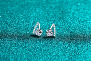 Macro detail of S925 sterling silver V-shape moissanite stud earring on teal glitter background