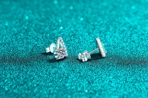 Close-up of V-shaped S925 sterling silver stud earrings with moissanite on green glitter