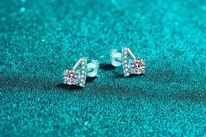 Detail view of S925 silver moissanite earrings with V-shape pave setting on green background