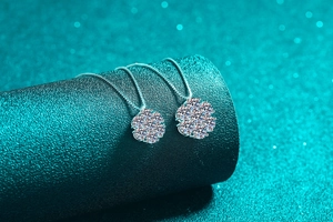 Macro side view of silver sunflower necklaces with pavé moissanite on a blue display