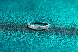 Macro view of V-shaped sterling silver ring with pavé moissanite on green glitter background