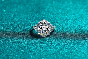 Macro shot of silver ring with oval and trillion cut moissanite stones on blue glitter