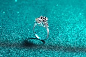 Detail of three-stone S925 silver ring featuring oval and triangle cut moissanite stones