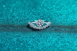 Macro detail of S925 silver moissanite ring showing crown setting on teal glitter background