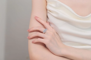 Detailed shot of a silver ring with rectangular blue stone and accent crystals on finger