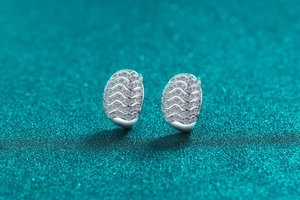 Macro shot of silver wave earrings featuring moissanite pavé and unique oval texture