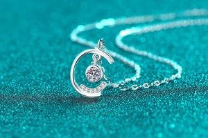 Macro detail of S925 sterling silver C-shape pendant with moissanite on blue background
