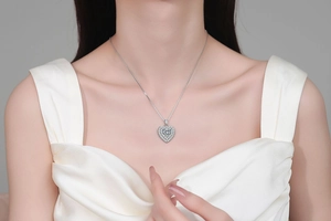 Gros plan du pendentif cœur en moissanite sur chaîne argent S925 avec une robe en soie