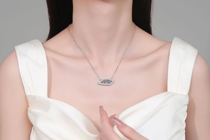 Gros plan du pendentif œil maléfique en argent S925 porté sur une robe en soie blanche
