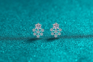 Macro shot of silver snowflake earrings with moissanite crystals on blue glitter