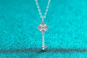 Macro shot of S925 silver key pendant necklace with moissanite diamonds on blue background