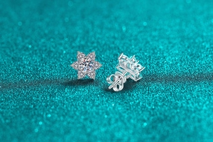 Dettaglio macro di orecchini a stella in argento S925 con moissanite e chiusura a farfalla