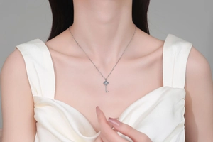 Close-up of S925 silver key pendant necklace with blue moissanite on female model
