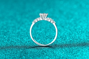 Close-up of elegant S925 silver moissanite ring with six-prong setting on glitter background