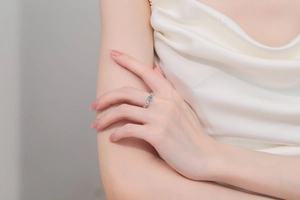 Détail d'une bague en argent s925 avec moissanite bleue sur fond de soie porté par modèle