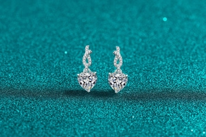 Detailed macro view of heart-shaped moissanite earrings with infinity silver setting