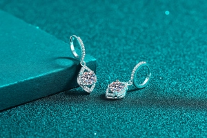 Macro shot of S925 silver moissanite earrings with drop pendant on green surface