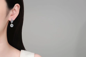 Close-up of S925 sterling silver moissanite drop earrings on a model with halo setting