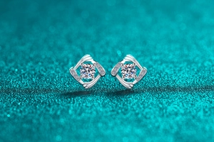 Macro shot of geometric sterling silver moissanite stud earrings on a teal glitter backdrop
