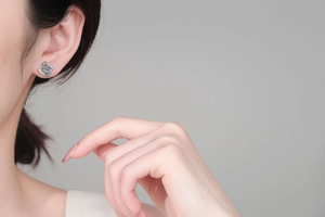 Close-up of S925 sterling silver geometric swirl stud earrings worn on model's ear