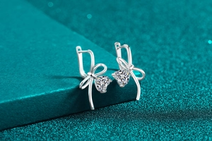 Detailed view of sterling silver bow earrings with heart-cut moissanite stone