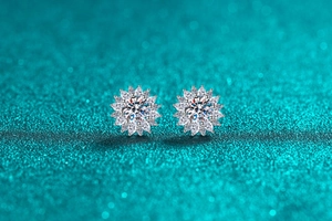 Macro shot of S925 sterling silver sunflower moissanite stud earrings on blue glitter