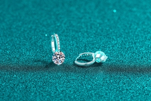 Gros plan de boucles d'oreilles créoles en argent 925 et moissanite sur fond bleu