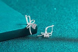 Macro detail of S925 sterling silver bow earrings with heart-shaped moissanite stones