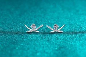 Detailed close-up of S925 sterling silver moissanite cross earrings on a glittery background
