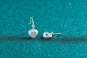 Macro detail of S925 sterling silver heart earrings with moissanite on teal glitter