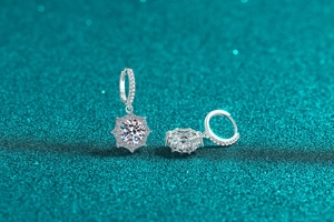 Close-up of S925 sterling silver snowflake earrings with moissanite stones on dark background