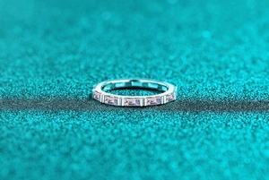 Macro detail of S925 silver ring with baguette cut pink moissanite stones on blue texture