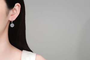 Close-up of S925 sterling silver moissanite snowflake earring worn on a model's ear