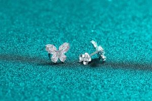 Close-up of S925 silver butterfly earrings with sparkling moissanite on blue background