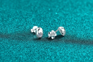 Macro shot of silver moissanite stud earrings with oval geometric design and butterfly backs