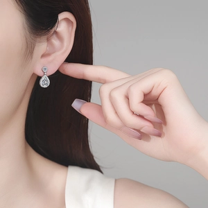 Elegant S925 sterling silver pear-cut moissanite drop earrings worn by a model