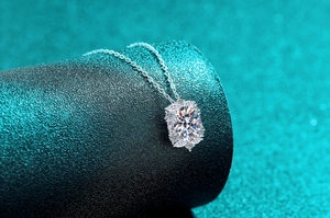 Dettaglio del ciondolo ovale in moissanite con incastonatura halo su piedistallo materico