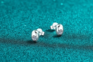 Macro shot of silver S925 stud earrings with sparkling moissanite on blue background